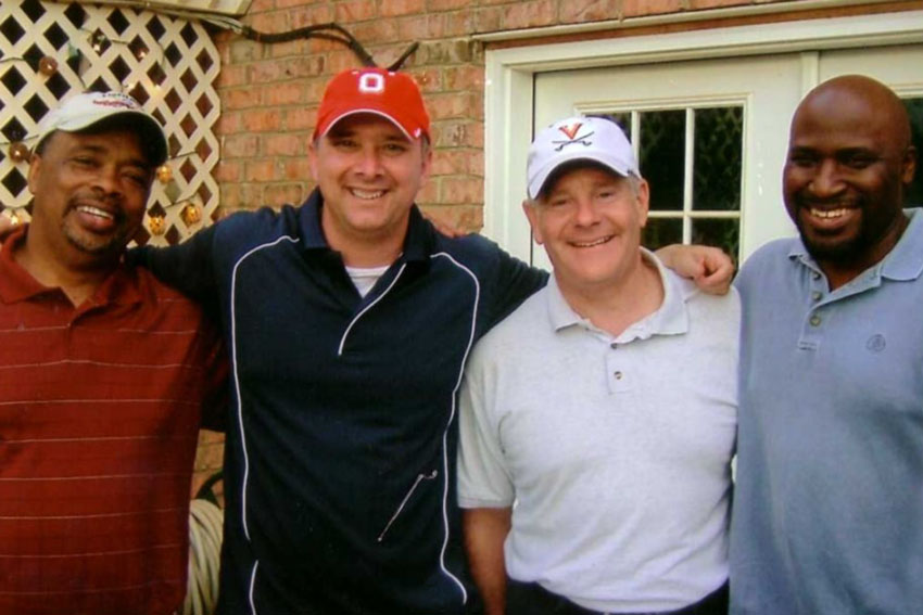 Four men posing for photo outside
