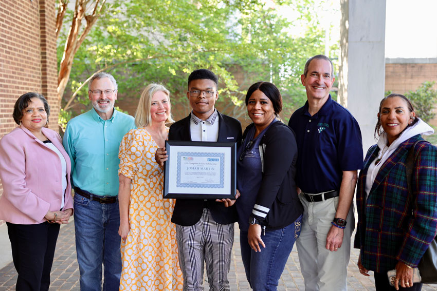 Scholarship recipient Joey Martin standing outside School Administration Building surrounded by donors, teachers, administrators and family