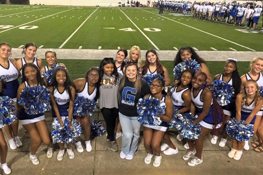 E. C. Glass football cheerleading squad with two coaches posing on sideline