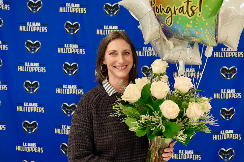 Ashley Marot holding flowers and balloons in front of E. C. Glass backdrop