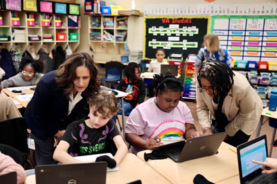 Principal and Superintendent working with students using Chromebooks