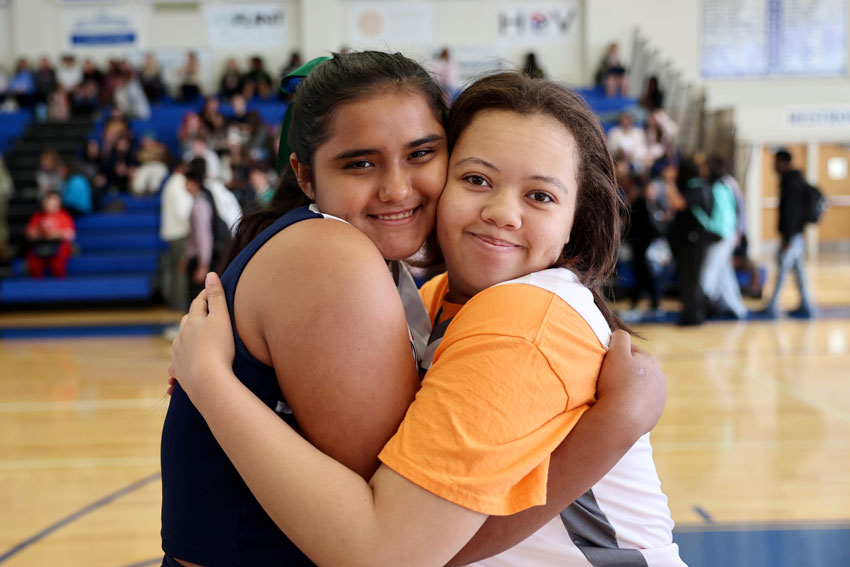 Two students hugging on basketball court