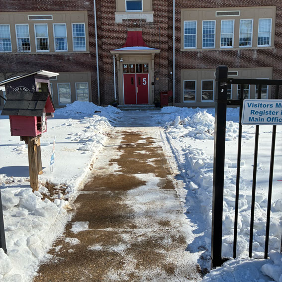 School property covered in snow except shoveled sidewalk