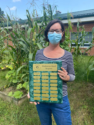 Kris Lloyd holding Huskitarian Award in school garden