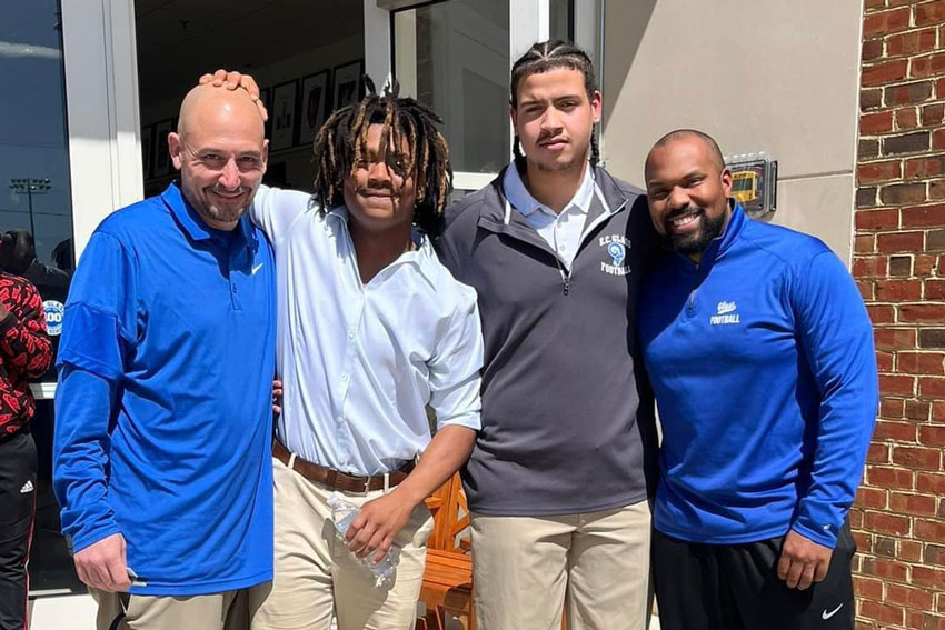 Two football player scholarship recipients and two coaches