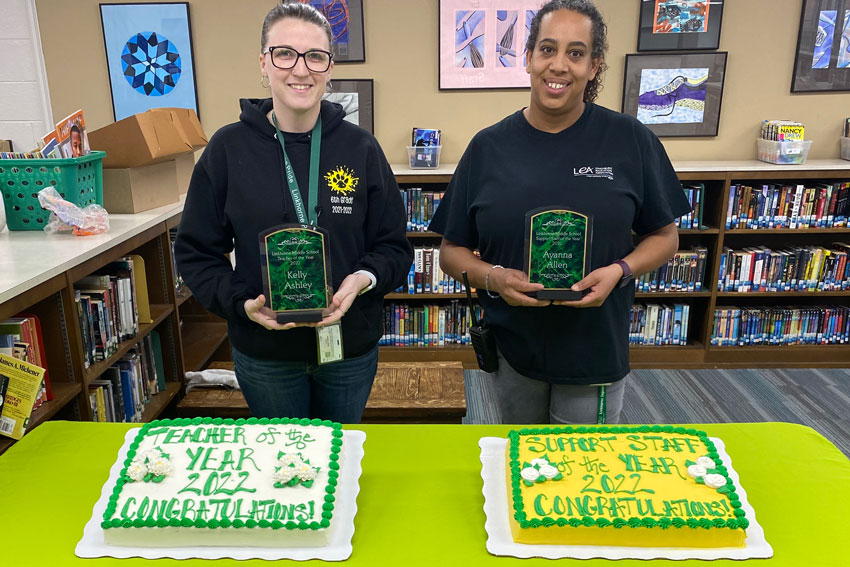 Kelly Ashley and Ayanna Allen holding awards standing front of cakes