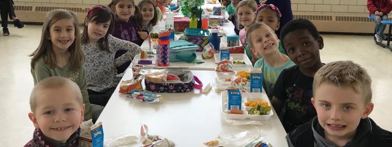 Students sitting at lunch table smiling