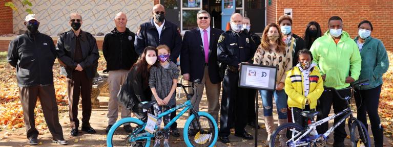 Community leaders standing outside with students and families with new bikes