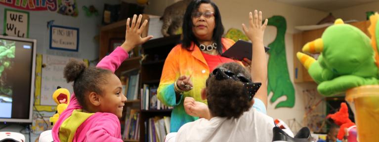 Girls raising hands with teacher