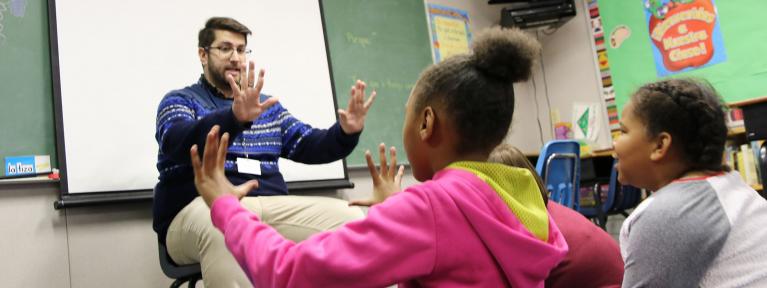 Teacher sitting in front of students doing activity