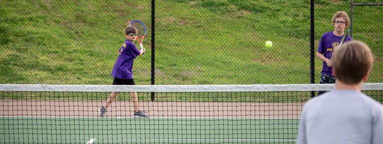 Boys playing doubles tennis