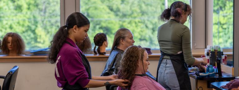 Cosmetology student preparing to cut woman's hair