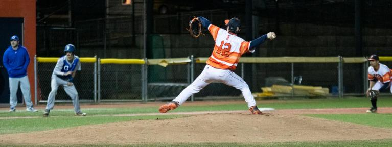 Baseball player throwing pitch with base runner in background