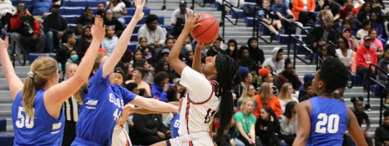 Girl shooting basketball over defender