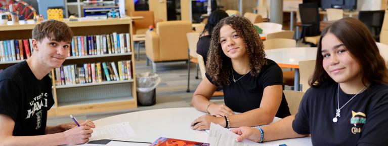 Three students sitting at table in school library