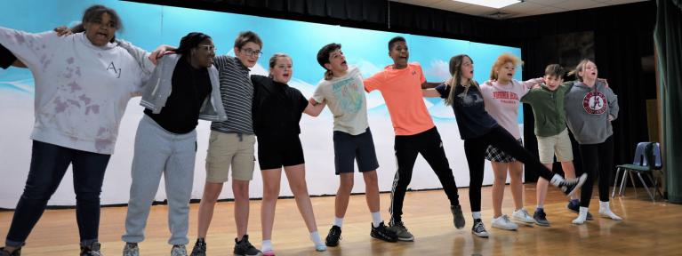 Students on stage rehearsing for musical