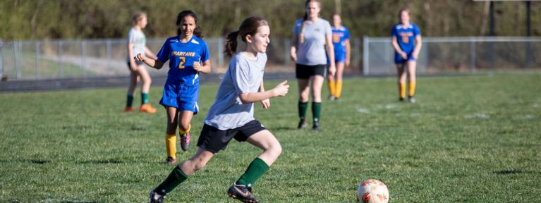 Girls playing soccer on field