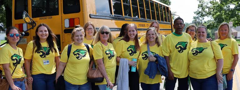 School staff standing next to school bus