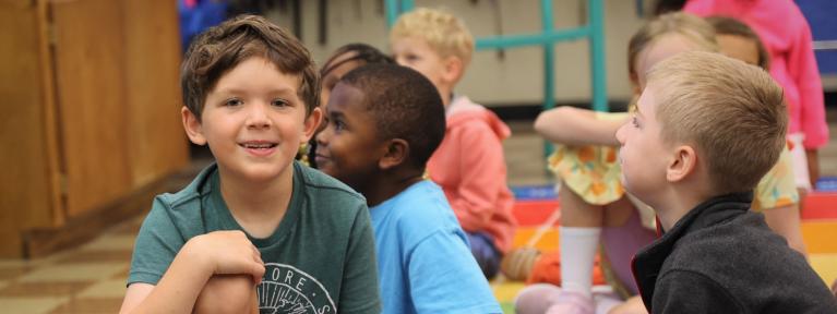 Boy sitting on floor with classmates in background