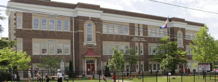 School exterior with students playing in front