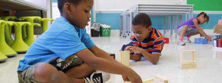 Two boys and girl building blocks on floor