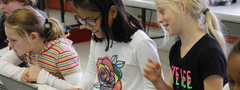 Three girls smiling using laptops