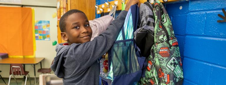 Boy hanging up backpack